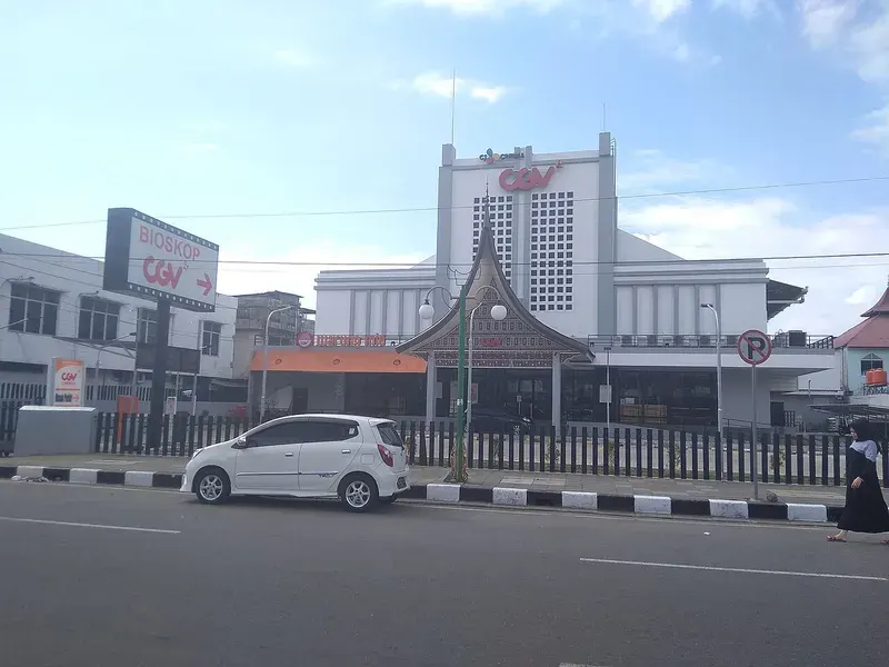 Gedung bioskop CGV Padang berwarna putih dengan papan nama CGV dan gerbang beratap gonjong di tepi jalan