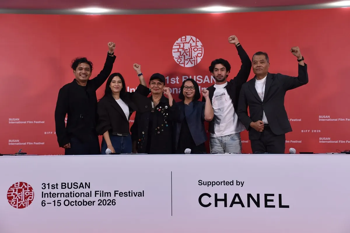 Enam orang berdiri berjajar sambil mengangkat kepalan tangan di depan latar merah bertuliskan 31st Busan International Film Festival