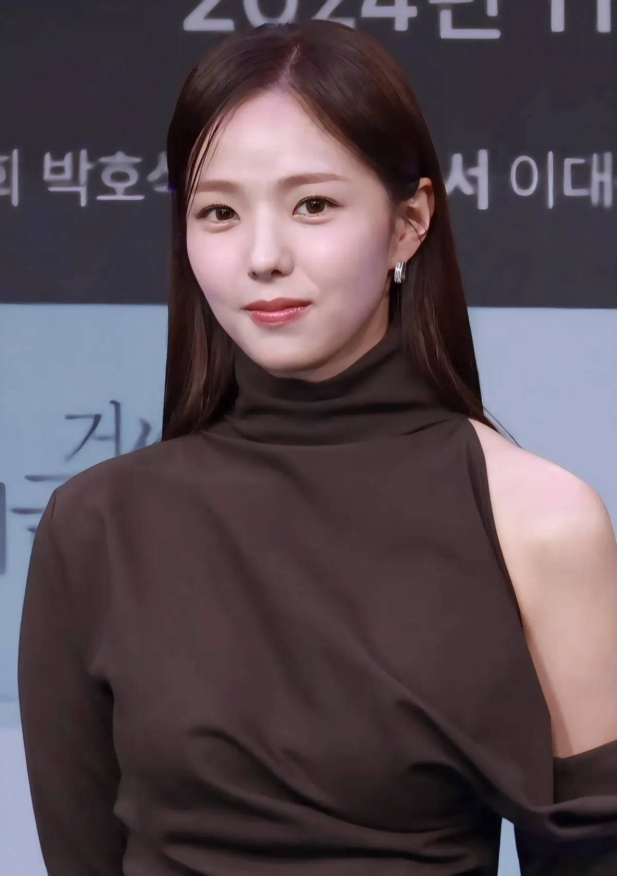 Chae Soo-bin berbaju turtleneck cokelat tersenyum di depan papan acara jumpa pers drama Korea pada November 2024