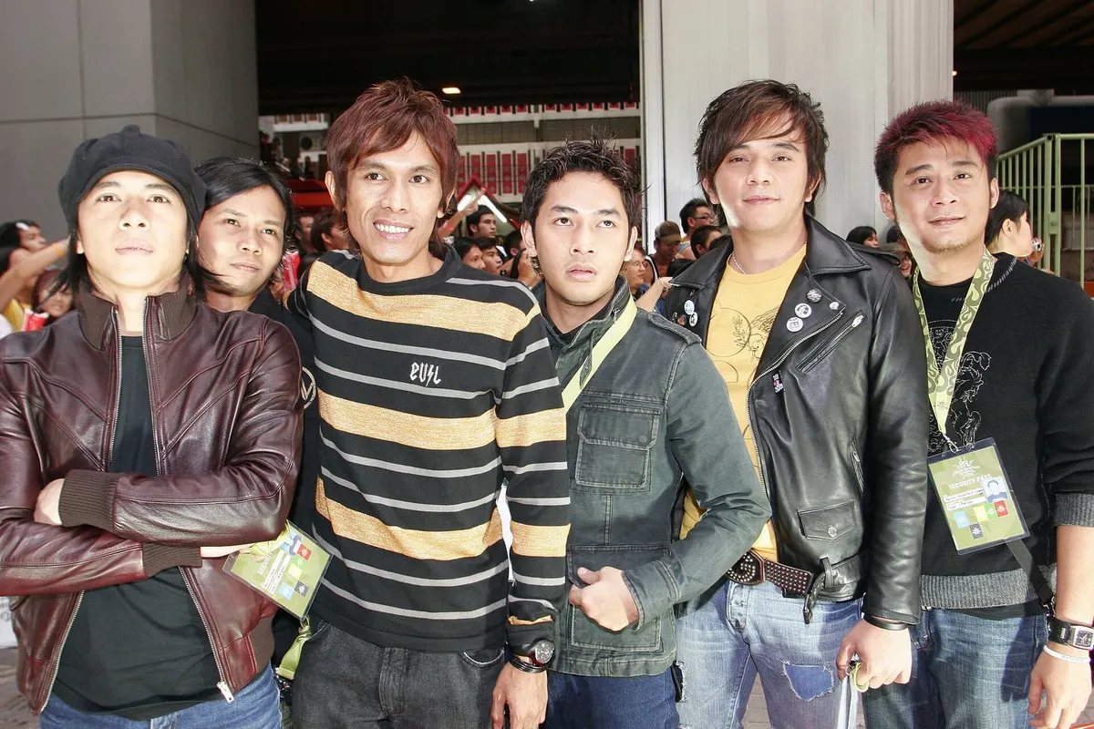 Enam personel band Peterpan berfoto bersama di area acara di Bangkok, sebagian mengenakan jaket kulit dan kartu akses di leher