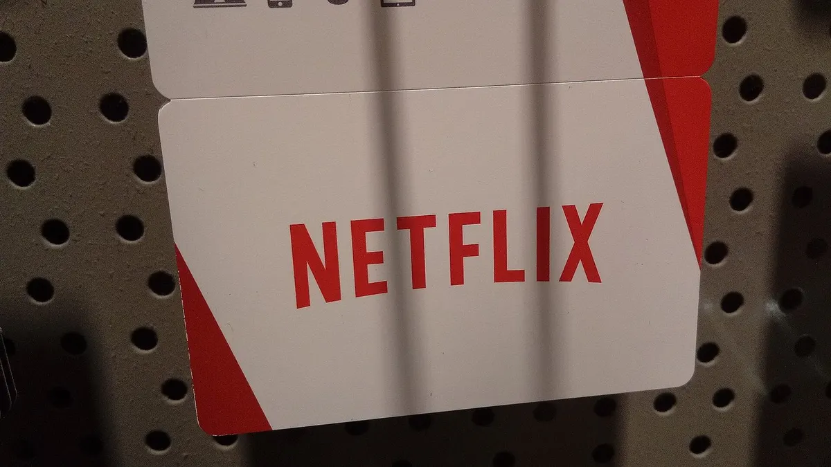 Kartu hadiah Netflix berwarna putih dengan tulisan NETFLIX merah tergantung di rak berlubang sebuah toko