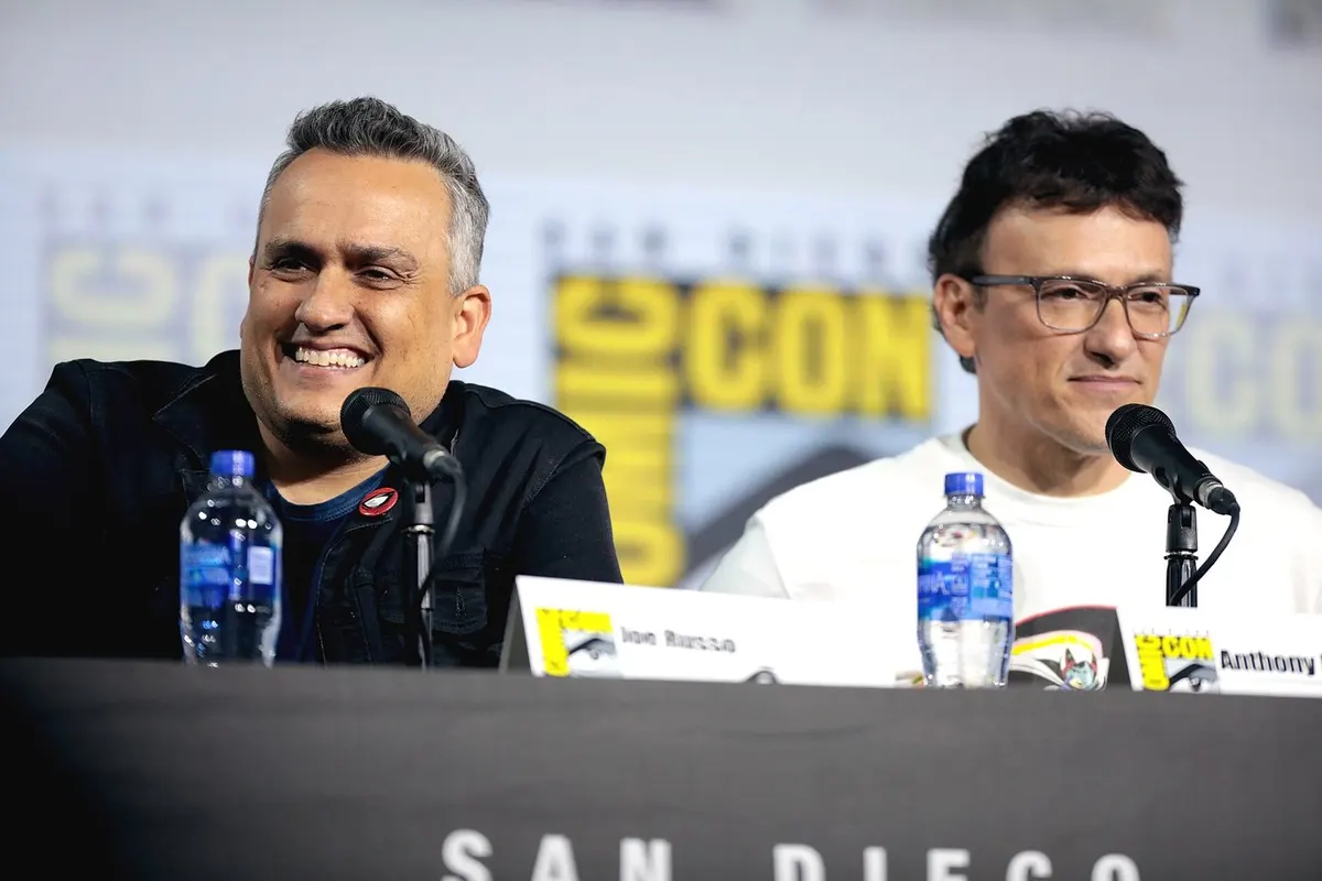 Joe Russo dan Anthony Russo duduk berdampingan di meja panel San Diego Comic-Con 2019 dengan mikrofon dan papan nama masing-masing