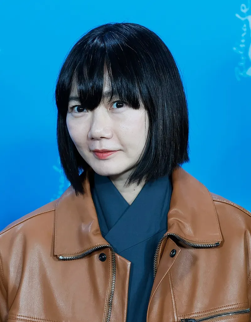 Bae Doona berponi dan berjaket kulit cokelat di depan latar biru Berlinale