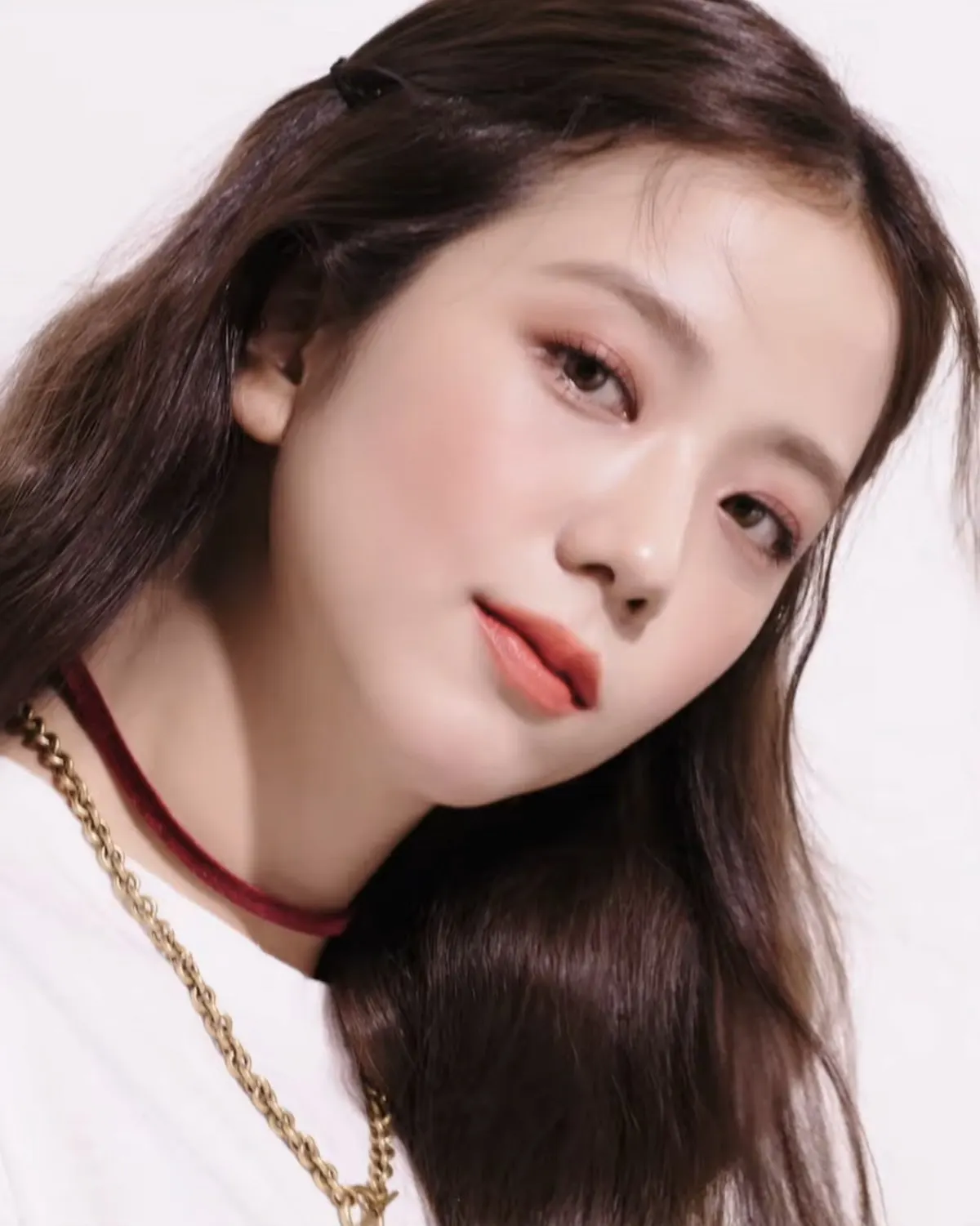 Jisoo berambut panjang menatap kamera dengan kalung rantai emas dan kalung beludru merah