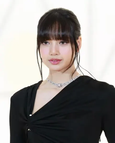 Lisa berponi dengan gaun hitam dan kalung berkilau di depan latar putih