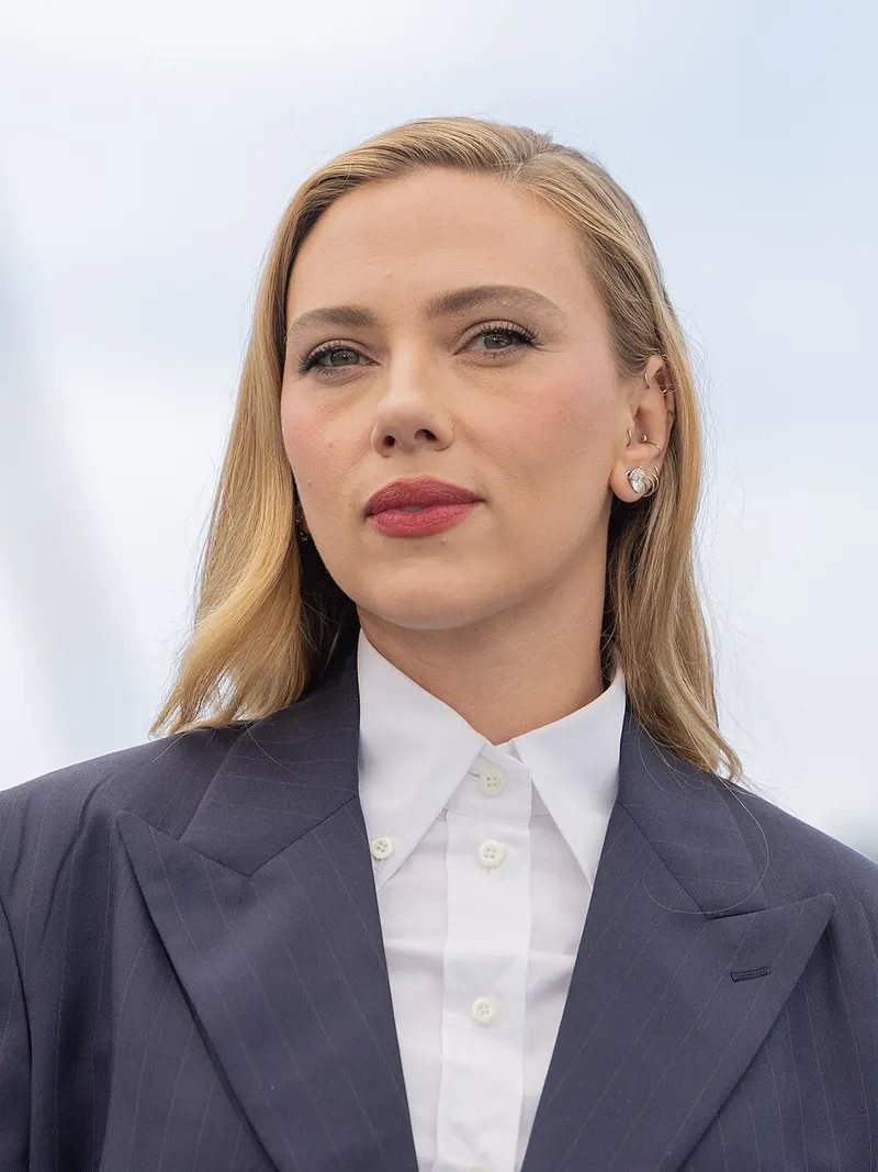 Scarlett Johansson berambut pirang, berjas bergaris dan berkemeja putih di luar ruangan