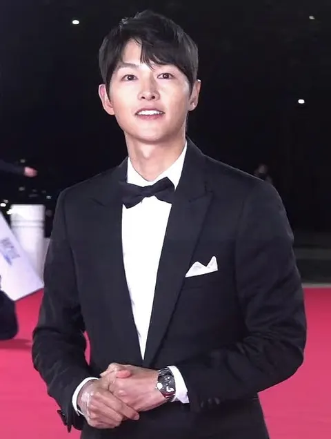 Song Joong-ki bertuksedo hitam dengan dasi kupu-kupu di karpet merah