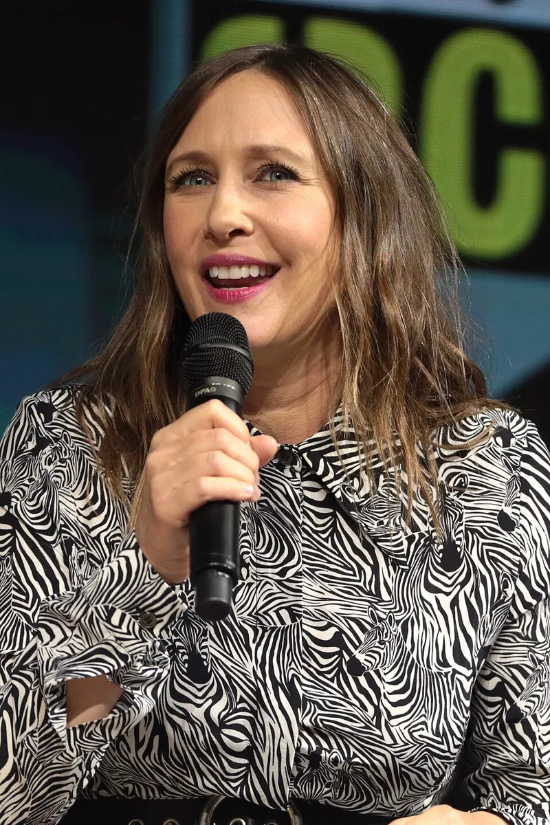 Vera Farmiga berbaju motif zebra berbicara memegang mikrofon di panel