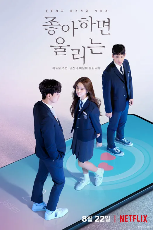 Poster resmi Love Alarm (2019) musim pertama: tiga siswa berseragam biru tua berdiri di atas layar ponsel raksasa bergambar aplikasi Love Alarm, dengan judul Korea 좋아하면 울리는 dan tulisan 8월 22일 Netflix